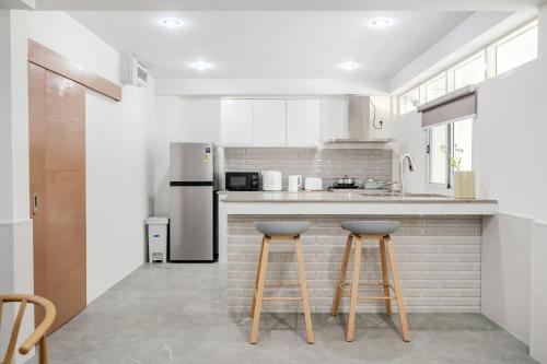 a kitchen with white appliances and two bar stools at Haus Ekkamai 2 in Klong Toi