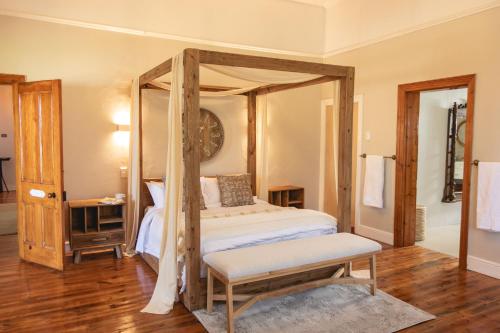 ein Schlafzimmer mit einem Himmelbett mit einer Bank in der Unterkunft The View Guesthouse & Cottage in Caledon