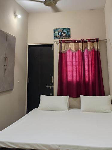 a bedroom with a large bed with a red curtain at Dwarka Home Stay in Dwarka