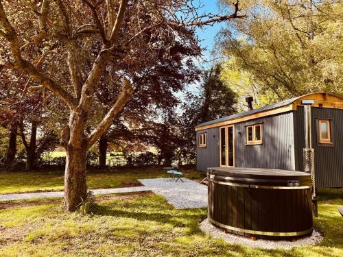 a tiny house with a tub next to a tree at Worcester Escape in Hallow