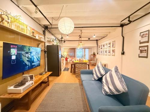 a living room with a blue couch and a tv at Dominol House l 5 min to Nimman l MAYA l Old Town l 附近的房子 in Chiang Mai