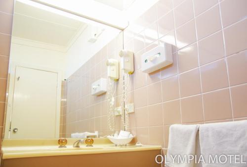 a bathroom with a sink and a mirror at Olympia Motel in Queanbeyan