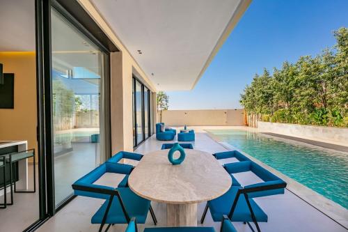 un comedor con mesa y sillas junto a una piscina en Luxury Villa, Design, Comfort, Heated Pool, Games, en Marrakech