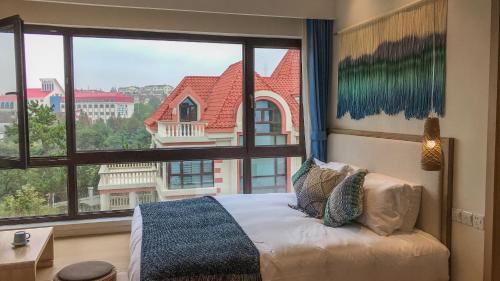 a bedroom with a bed and a large window at Hando • Cape Seven Seaside Villa in Qingdao