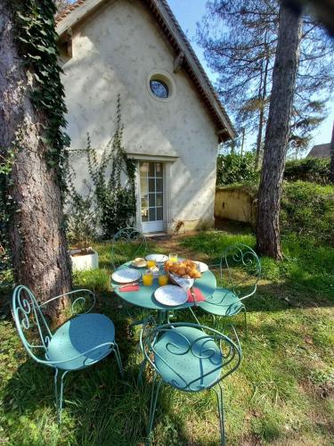a table and chairs with food on it in front of a house at Maison d'hôtes La Danasha in Viglain