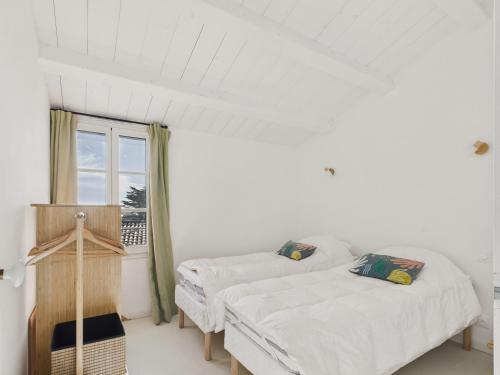 two beds in a white room with a window at 400m de la plage, jardin, maison pour 8 in Le Gillieux