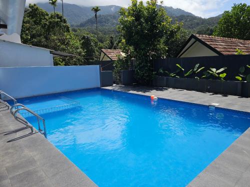 a blue swimming pool with a fence and mountains in the background at Mount wave Pool villa in Wayanad