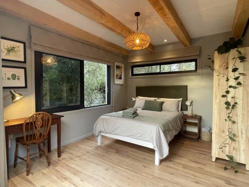 ein Schlafzimmer mit einem Bett, einem Schreibtisch und Fenstern in der Unterkunft Olive Cottage Scarborough Seaside Village in Scarborough