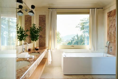 een badkamer met twee wastafels en een bad en een raam bij L'Albereta Relais & Chateaux in Erbusco