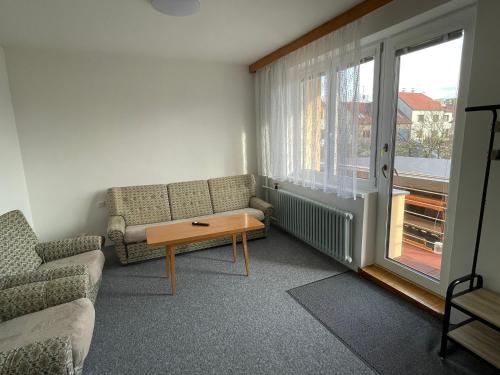 Una sala de estar con un sofá y una mesa y una ventana. en Ubytování u zastávky, en Modrá