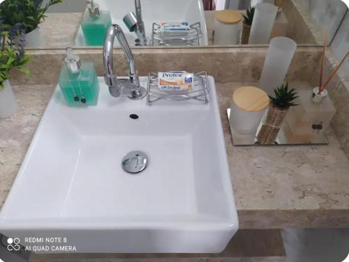 a white sink with a toothbrush holder on a counter at Hospedagem Altas da Quitéria Suíte 01 in Catas Altas