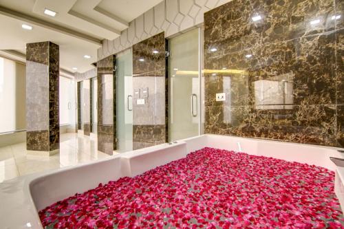 ニューデリーにあるHotel Park Tree Near Airport Delhiのバスルーム(ピンクのバラの花びらを使用したバスタブ付)