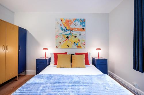 a bedroom with a bed with two blue cabinets and two lamps at Welcome London Theatreland House in London