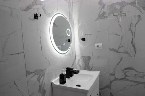 a white bathroom with a sink and a mirror at Vaip House B in Berat
