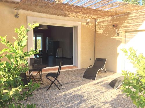 a patio with two chairs and a table and a window at Les Karakis, piscine au sel, jardin 5000m2 in Les Arcs sur Argens