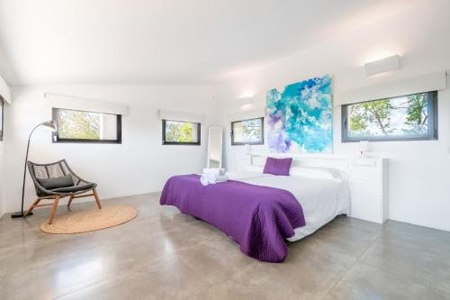 een witte slaapkamer met een groot bed en een stoel bij Dalt Son Morro in Santa Margalida