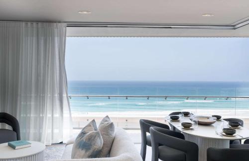 a living room with a table and a view of the ocean at Monet by Khove - Kirra Beach in Gold Coast