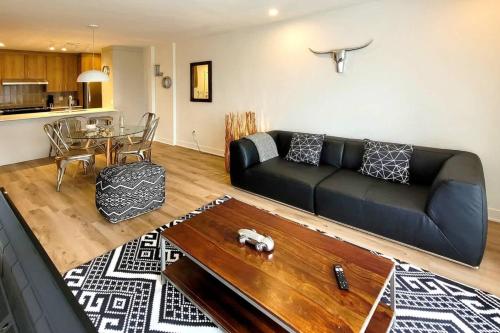 ein Wohnzimmer mit einer schwarzen Couch und einem Tisch in der Unterkunft Corporate Stays Blum 2 Bedrooms in Brossard