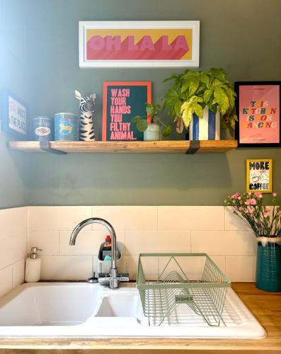 a kitchen sink with a faucet and a shelf at Hurrell Cottage in Cambridge