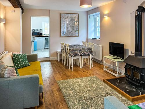 un salon avec une table et une cheminée dans l'établissement Bluebell Cottage, à South Brent