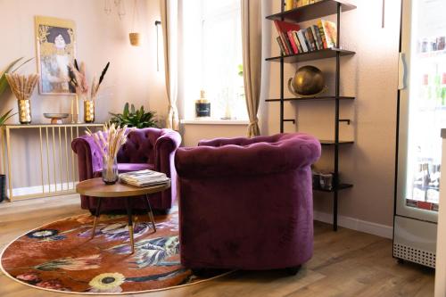 a living room with two purple chairs and a table at Hotel Garni BALTICpetite in Heringsdorf
