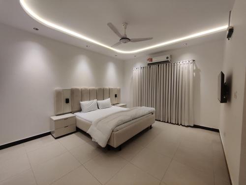 a white bedroom with a bed and a ceiling at Evergreen Lodge - Unmarried couples are not allowed in Rawalpindi