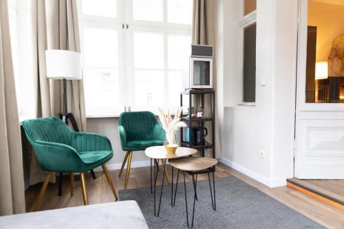 a living room with green chairs and a table at Hotel Garni BALTICpetite in Heringsdorf