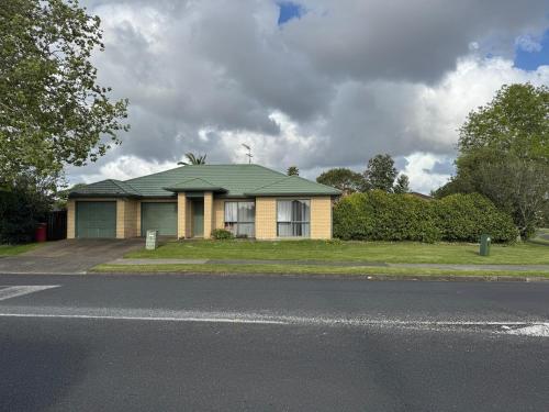 a yellow house with a green roof on a street at Relaxing 3BR Home by Wattle Downs Reserve in Auckland
