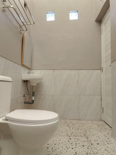 a bathroom with a white toilet and a sink at D'River Luxcamp in Cisarua