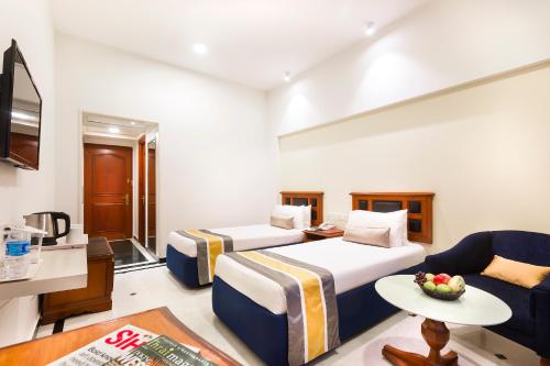 a hotel room with two beds and a couch at Regency Kanchipuram by GRT Hotels in Kanchipuram