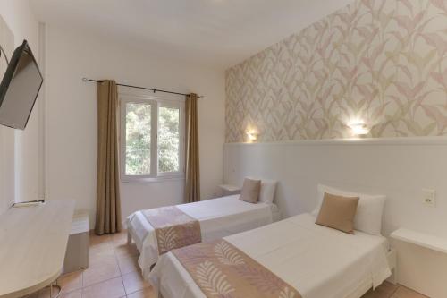 een hotelkamer met twee bedden en een raam bij Hotel des Etrangers in Bonifacio