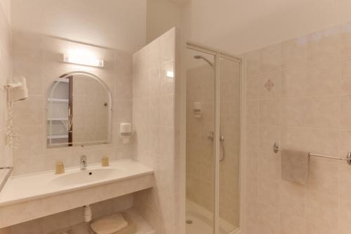 een badkamer met een wastafel en een glazen douche bij Hotel des Etrangers in Bonifacio