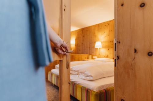 una persona che apre la porta di una stanza con due letti di Hotel Aurora a Lech am Arlberg