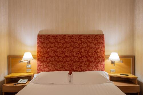 a bedroom with a bed with a red headboard and two lamps at Poli Hotel in San Vittore Olona