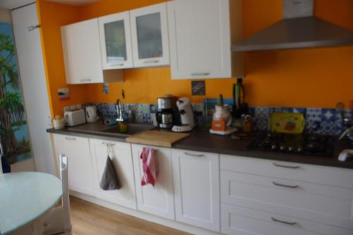 a kitchen with white cabinets and an orange wall at Comfort & quiet with garden in Saint-herblain in Saint-Herblain