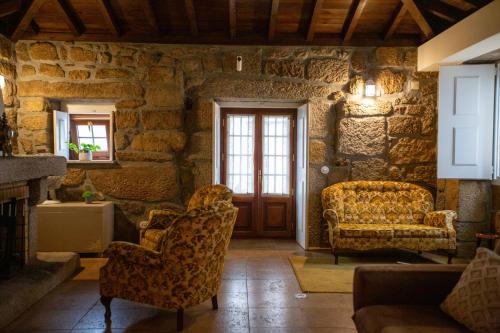a living room with two chairs and a door at Casa dos Livros - Guest House in Vila Nova de Tazem