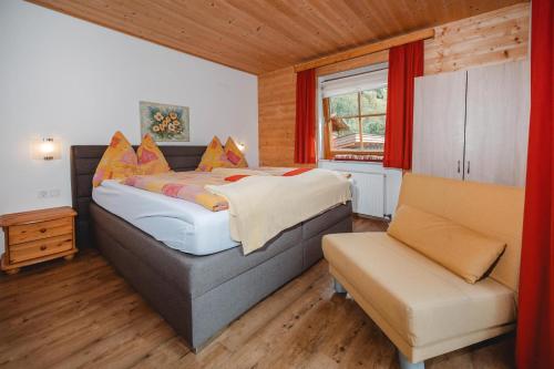 a bedroom with a bed and a couch and a chair at Kleintierhof Seidl-Eder in Rauris