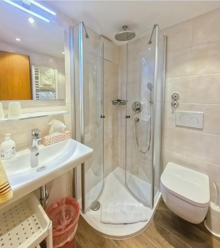 a bathroom with a shower and a sink and a toilet at Hotel Binderhäusl in Berchtesgaden