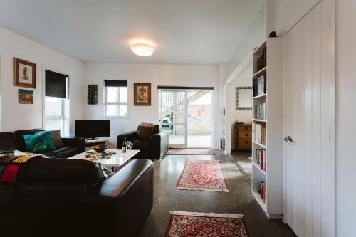 a living room with a couch and a table at Surf's Up - pet-friendly Fitzroy lifestyle home in New Plymouth