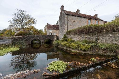 an old stone building next to a body of water at The Old Loft House in Chew Stoke in Chew Stoke