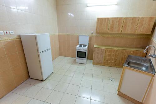 a small kitchen with a refrigerator and a sink at العييري للشقق المخدومة المدينة 3 in Al Madinah