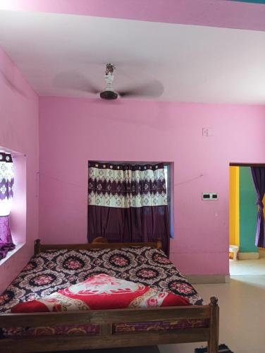 a bedroom with a bed with a pink wall at Sarat guest house in Digha