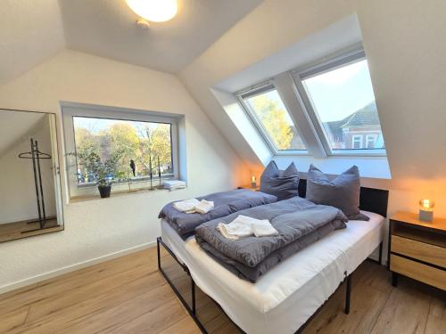 a bedroom with a bed with blue sheets and two windows at Appartement Turmblick in Marienhafe