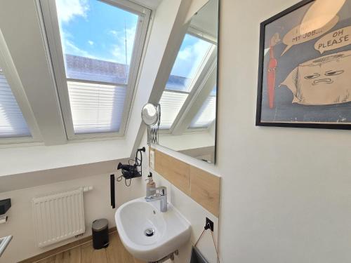 a bathroom with a sink and two windows at Appartement Turmblick in Marienhafe