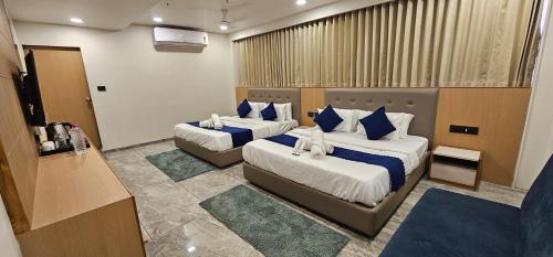 a hotel room with two beds with blue pillows at Hotel Earth Orbit in Gandhinagar