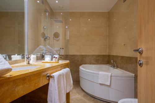 a bathroom with a tub and a sink and a mirror at Poli Hotel in San Vittore Olona