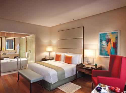 a bedroom with a large bed and a red chair at EL DE Olive Aero Suites Near Delhi International Airport in New Delhi
