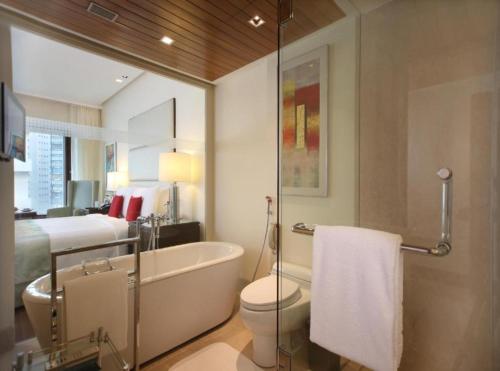 a bathroom with a tub and a toilet and a bed at EL DE Olive Aero Suites Near Delhi International Airport in New Delhi