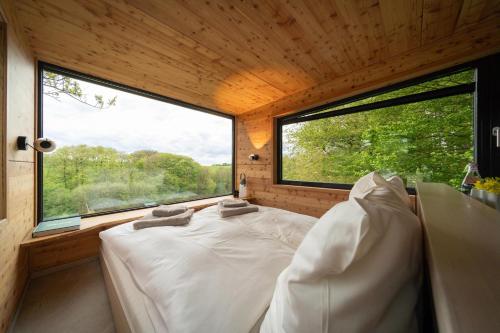 a bed in a room with a large window at Oak - K1 Baumhaus in Odenthal