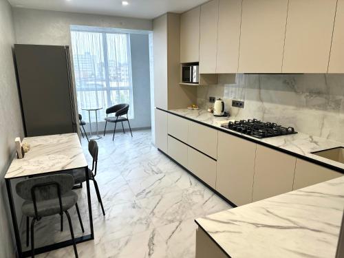 a kitchen with white cabinets and a stove top oven at 1 room Ridnyi Dim Apartment in Cherkasy